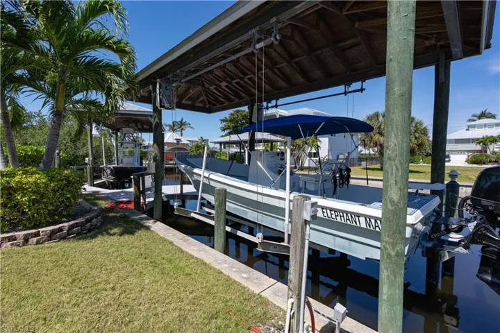 Dock area featuring boat lift, a water view, and a lawn