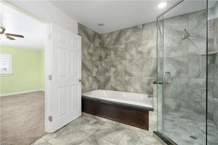 Full bath with a garden tub, ceiling fan, and a stall shower