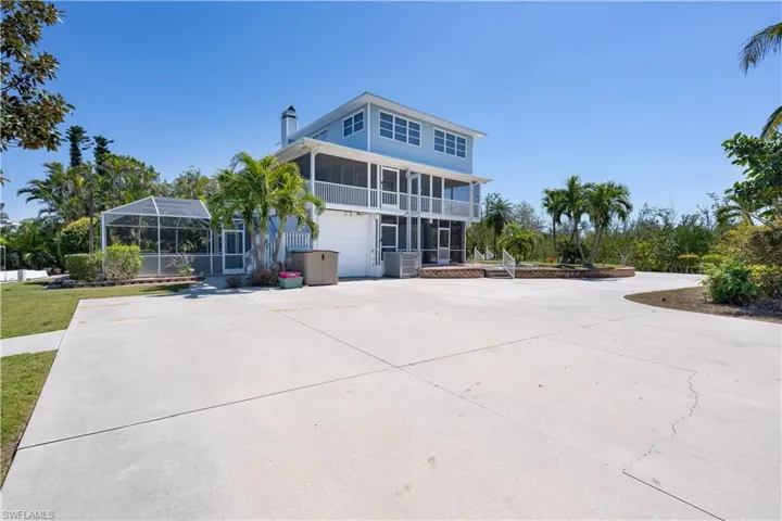 Back of house featuring glass enclosure, a garage, and concrete driveway