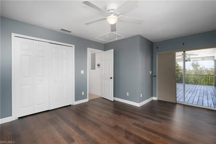 Unfurnished bedroom featuring access to exterior, attic access, wood finished floors, baseboards, and visible vents