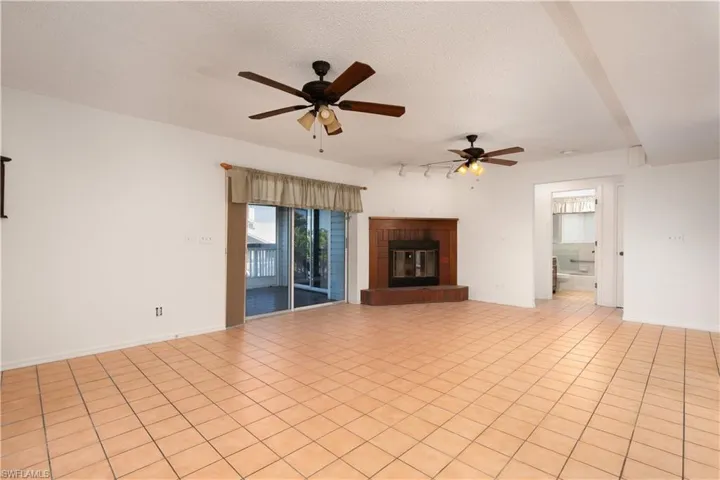 Unfurnished living room featuring baseboards, a textured ceiling, a fireplace, and a ceiling fan