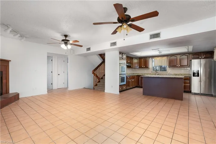 Kitchen with open floor plan, visible vents, a ceiling fan, and appliances with stainless steel finishes