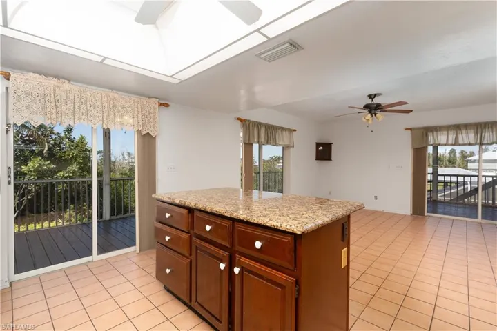 Kitchen with a skylight, a center island, light tile patterned floors, visible vents, and ceiling fan