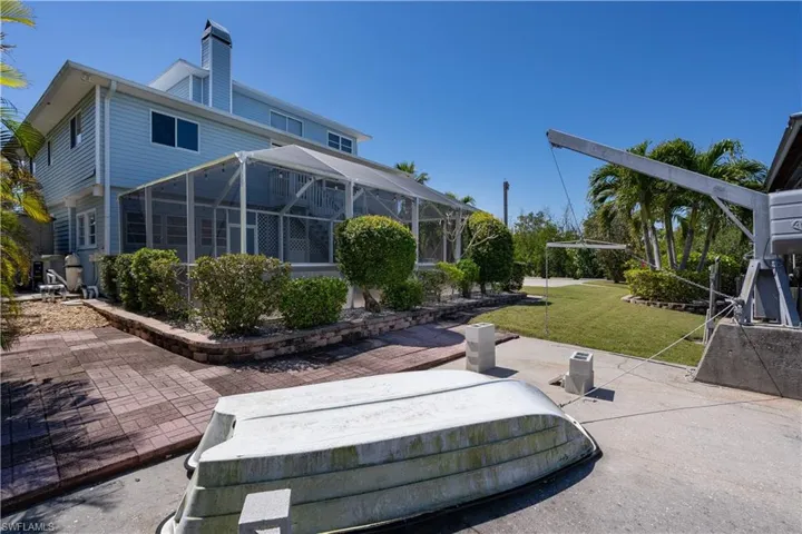 Back of house featuring a chimney, a patio, a lanai, and a lawn