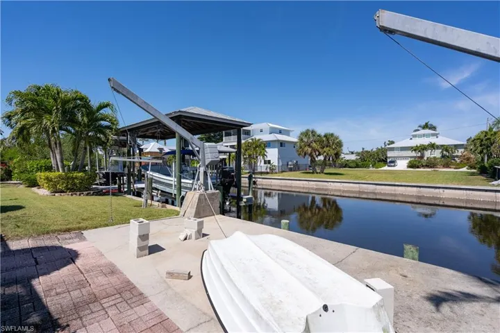 Dock area featuring a water view, boat lift, and a yard