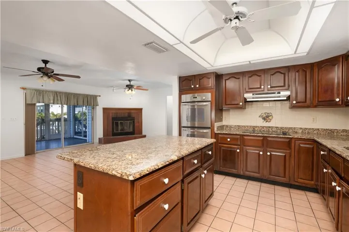 Kitchen featuring visible vents, a ceiling fan, under cabinet range hood, and stainless steel double oven