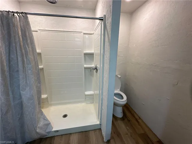 Bathroom with toilet, hardwood / wood-style flooring, and walk in shower