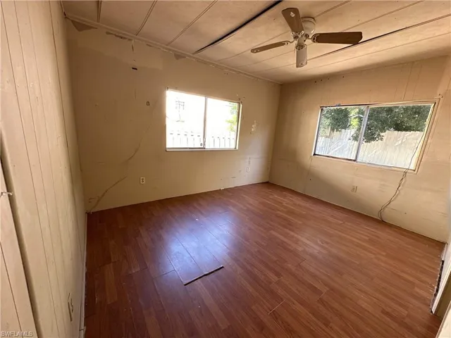 Empty room featuring ceiling fan, hardwood / wood-style flooring, and a wealth of natural light