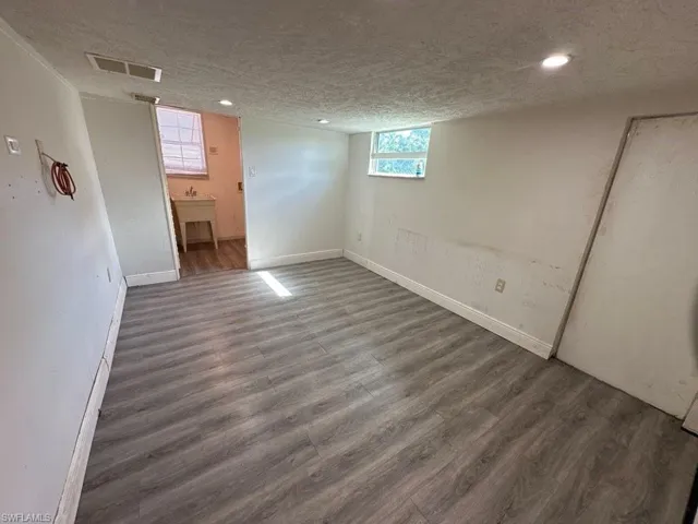 Basement with a textured ceiling and dark hardwood / wood-style flooring