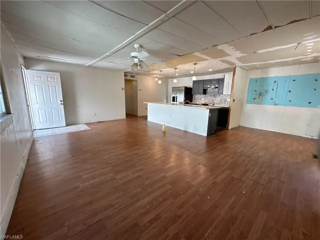 Unfurnished living room with ceiling fan and dark hardwood / wood-style floors