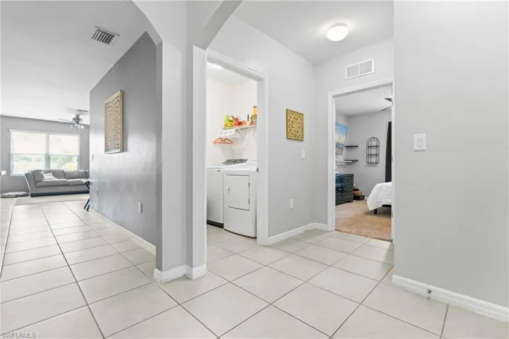 Hallway featuring light tile patterned flooring and washer and dryer