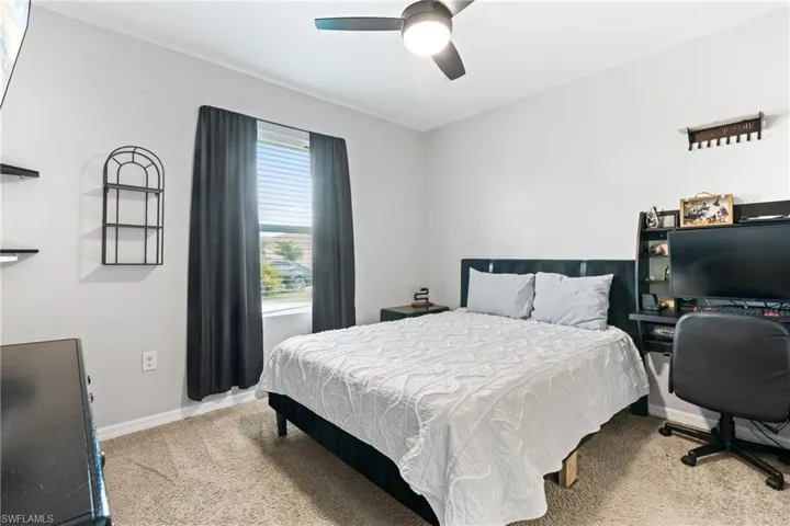 Carpeted bedroom featuring ceiling fan