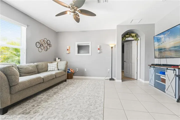 Living room with light tile patterned flooring and ceiling fan