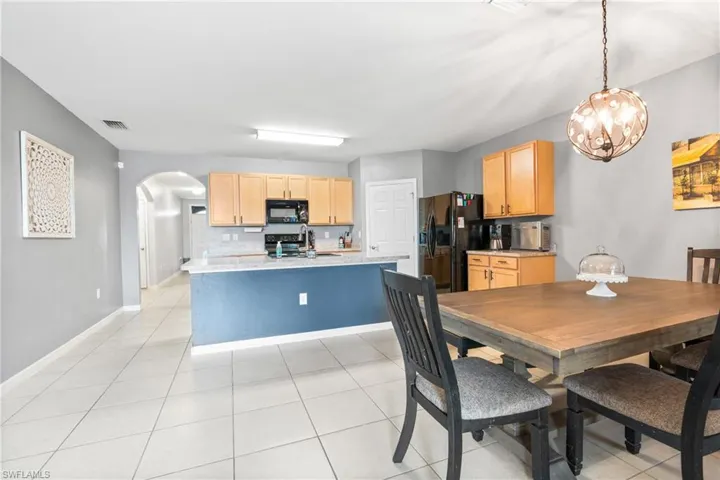 Tiled dining space featuring sink and a notable chandelier