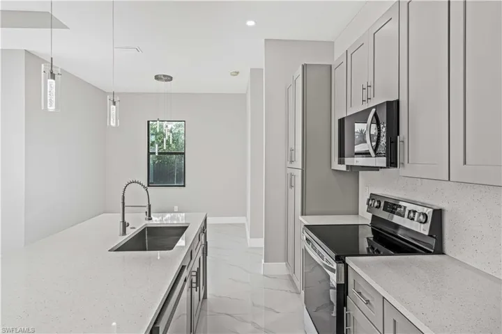 Kitchen with stainless steel appliances, light stone countertops, decorative light fixtures, light marble finish flooring, and recessed lighting