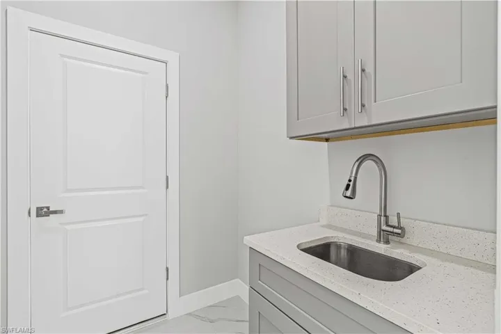 Washroom featuring light marble finish floors and a sink