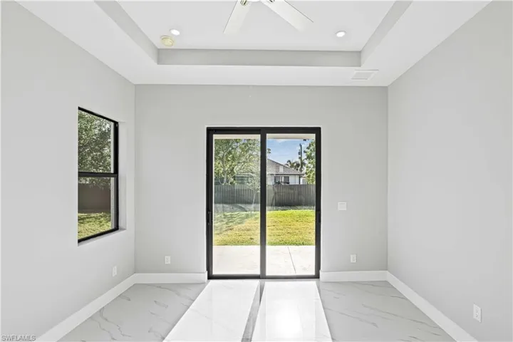Spare room with light marble finish floors, a tray ceiling, plenty of natural light, and recessed lighting
