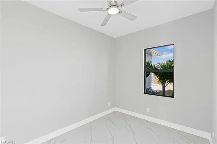 Second bedroom featuring light marble finish floors and ceiling fan
