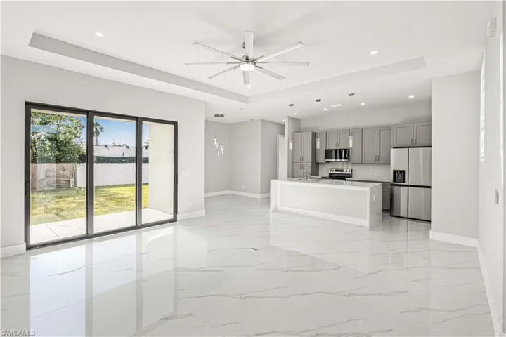 Living room with a tray ceiling, light marble finish floors, a ceiling fan, and recessed lighting