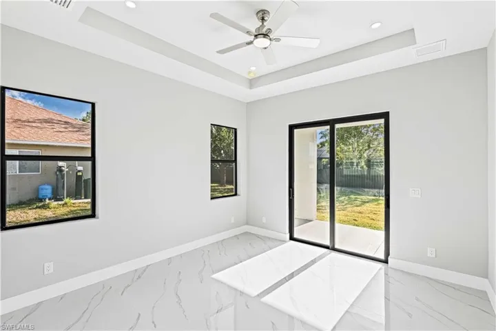 Empty room with light marble finish floors, a tray ceiling, recessed lighting, and ceiling fan