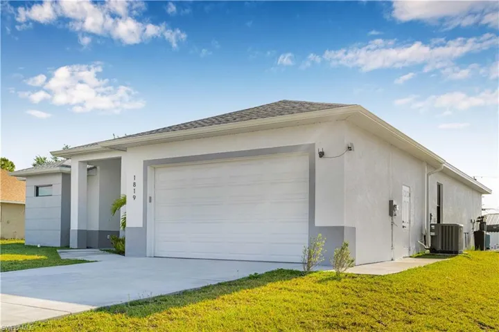View of side of home featuring stucco siding, a yard, and driveway