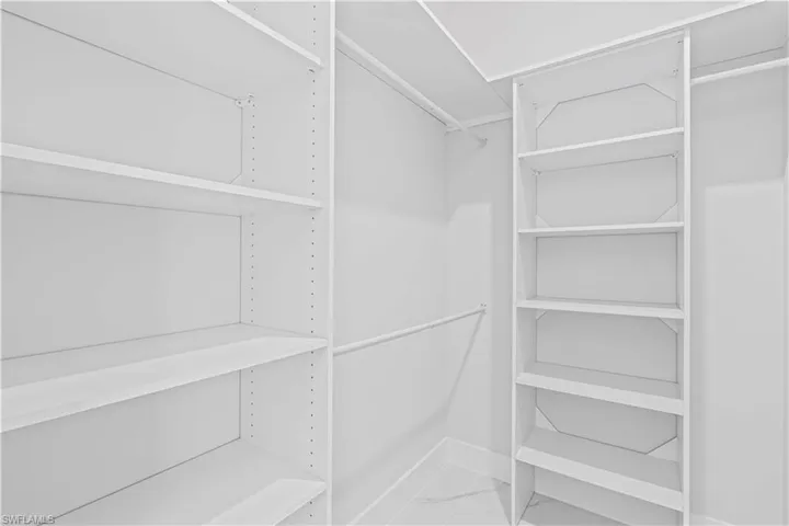 Walk in closet featuring light marble finish flooring
