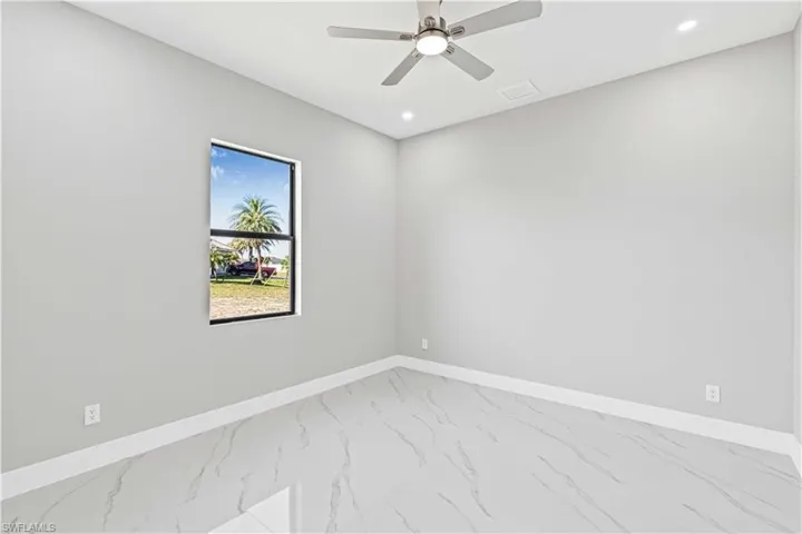 Third bedroom with marble look tile flooring, recessed lighting, and a ceiling fan