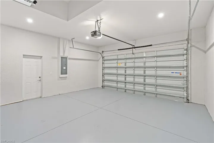 Garage featuring recessed lighting, electric panel, and a garage door opener