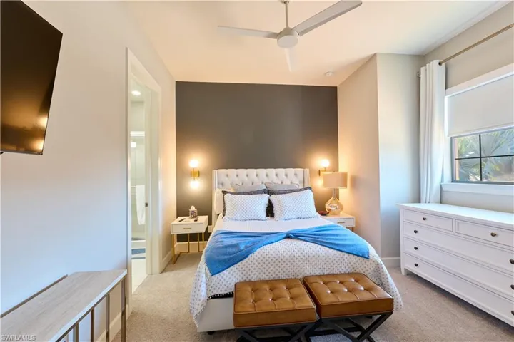Bedroom with light colored carpet, ceiling fan, and ensuite bathroom