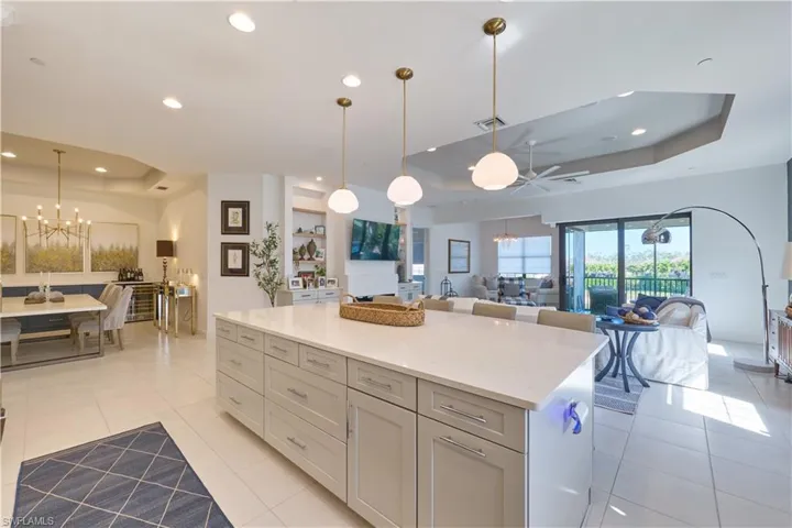 Kitchen with a chandelier, a tray ceiling, open floor plan, a center island, and recessed lighting