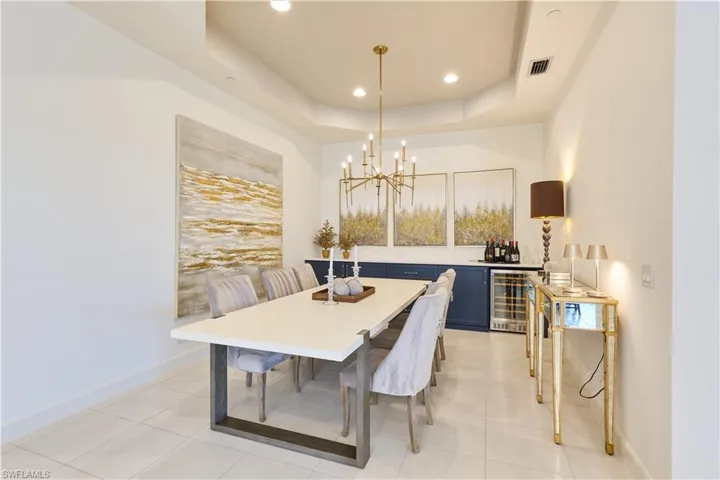 Dining space with a raised ceiling, a chandelier, wine cooler, recessed lighting, and light tile patterned floors