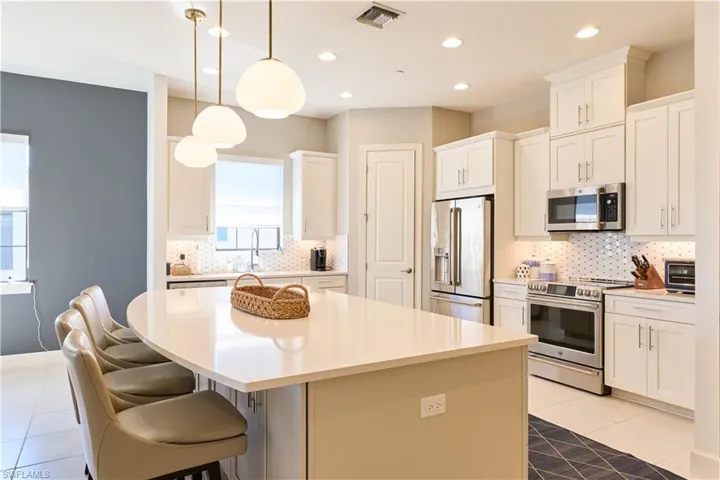 Kitchen featuring appliances with stainless steel finishes, decorative light fixtures, light tile patterned floors, a kitchen island, and recessed lighting