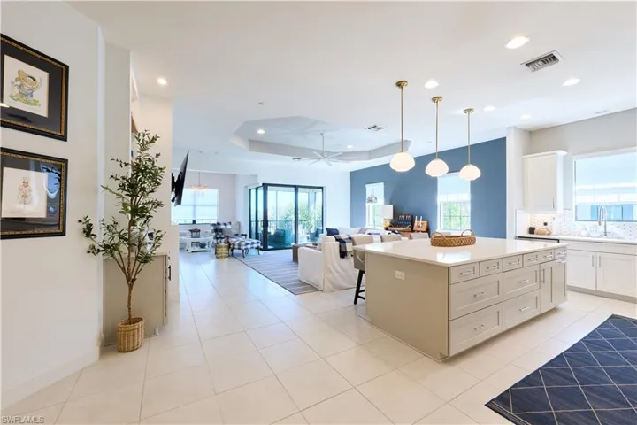 Kitchen with a center island, open floor plan, a breakfast bar area, decorative light fixtures, and a raised ceiling