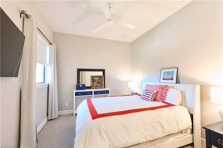 Carpeted bedroom with a ceiling fan and baseboards