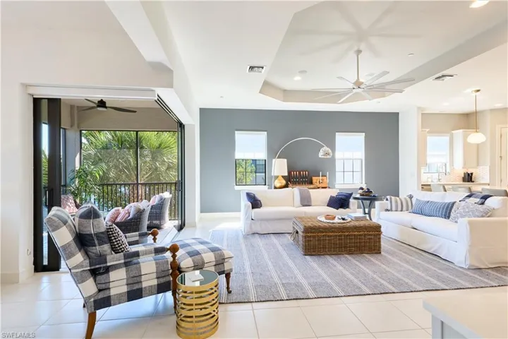 Living room with a ceiling fan, a raised ceiling, and light tile patterned floors