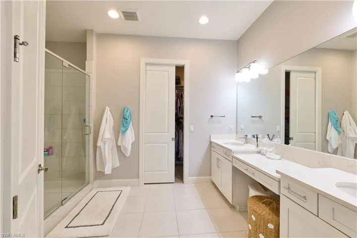 Master Bathroom with double vanity, a shower stall, a walk in closet, light tile patterned floors, and recessed lighting