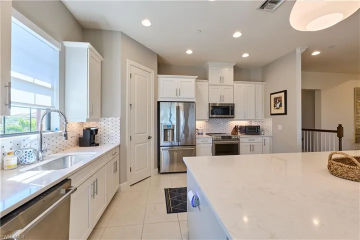 Kitchen featuring appliances with stainless steel finishes, light stone countertops, white cabinets, backsplash, and recessed lighting