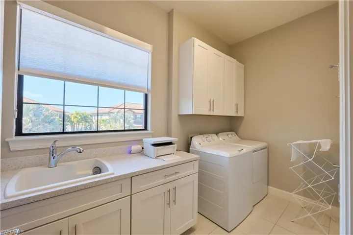 Washroom with cabinet space, washer and dryer, and light tile patterned flooring