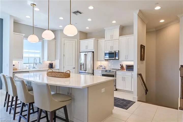 Kitchen with appliances with stainless steel finishes, a breakfast bar area, white cabinetry, a center island, and recessed lighting
