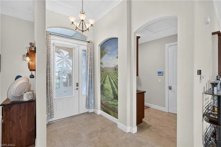 Foyer with ceramic tile flooring, double entry doors with decorative glass panels, and an arched doorway