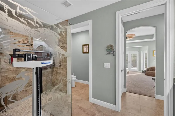 Glass-enclosed shower with etched decorative paneling and stone-finish wall tile