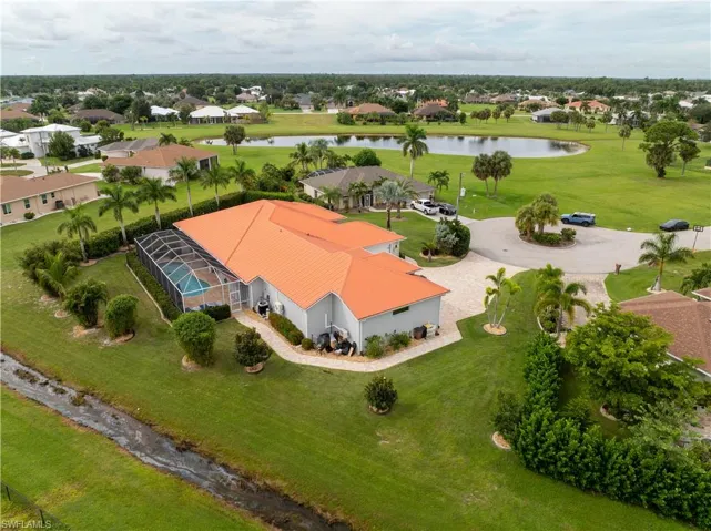 Expansive property featuring a screened-in swimming pool, a large paved driveway, and mature landscaping