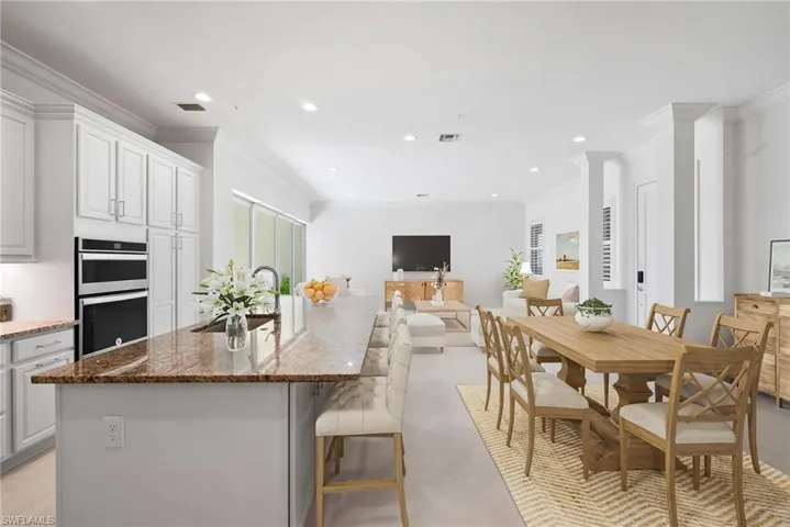 Kitchen featuring light tile patterned flooring, a kitchen island with sink, stainless steel double oven, and crown molding