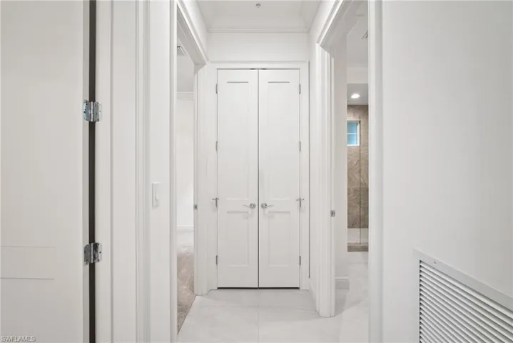 Hall with light tile patterned flooring and crown molding