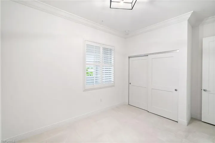 3rd bedroom featuring a closet, light tile patterned floors, and crown molding