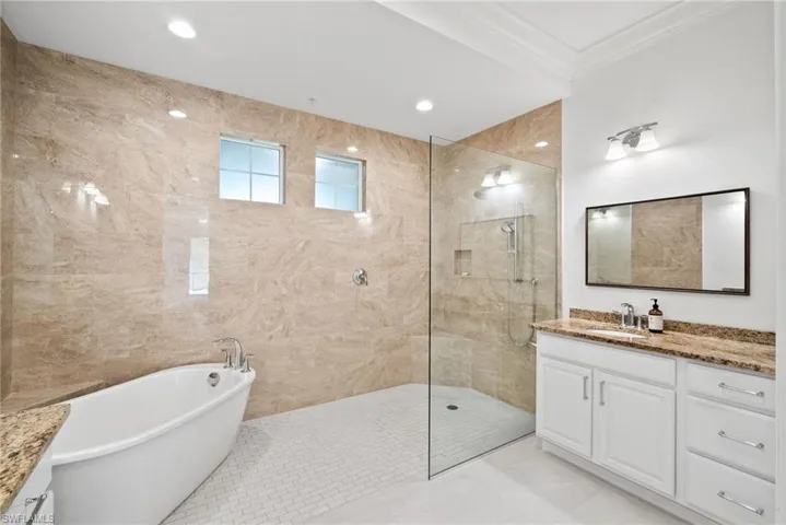 Bathroom with shower with separate bathtub, vanity, tile patterned flooring, and tile walls