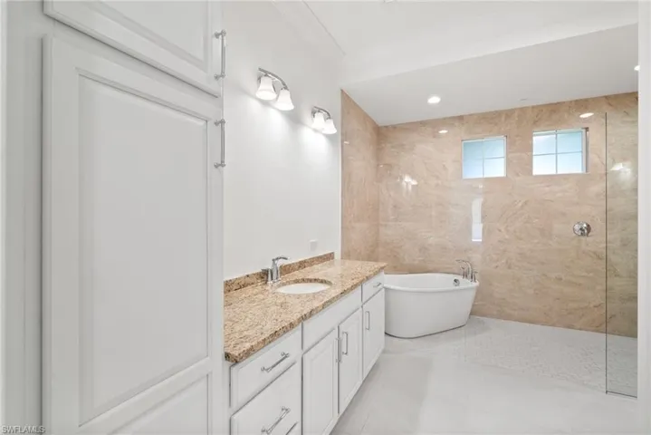Bathroom featuring crown molding, plus walk in shower, vanity, and tile patterned flooring