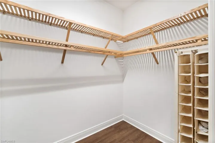 Walk in closet with hardwood / wood-style flooring