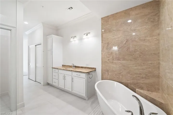 Bathroom with tile patterned floors, a bath, vanity, and crown l molding