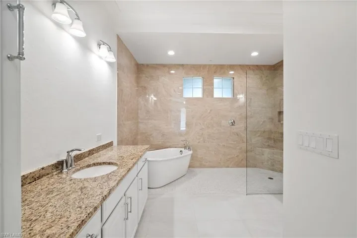 Bathroom with separate shower and tub, tile patterned floors, and vanity